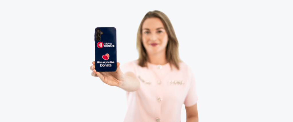 A lady holding a phone showing Give as you Live's contactless donation app - Tap to Donate.